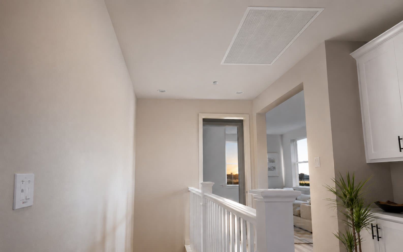 Whole house fan installed in the ceiling of an upstairs hallway with wall control switch visible
